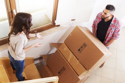 Professional movers carrying items through a Brent flat staircase
